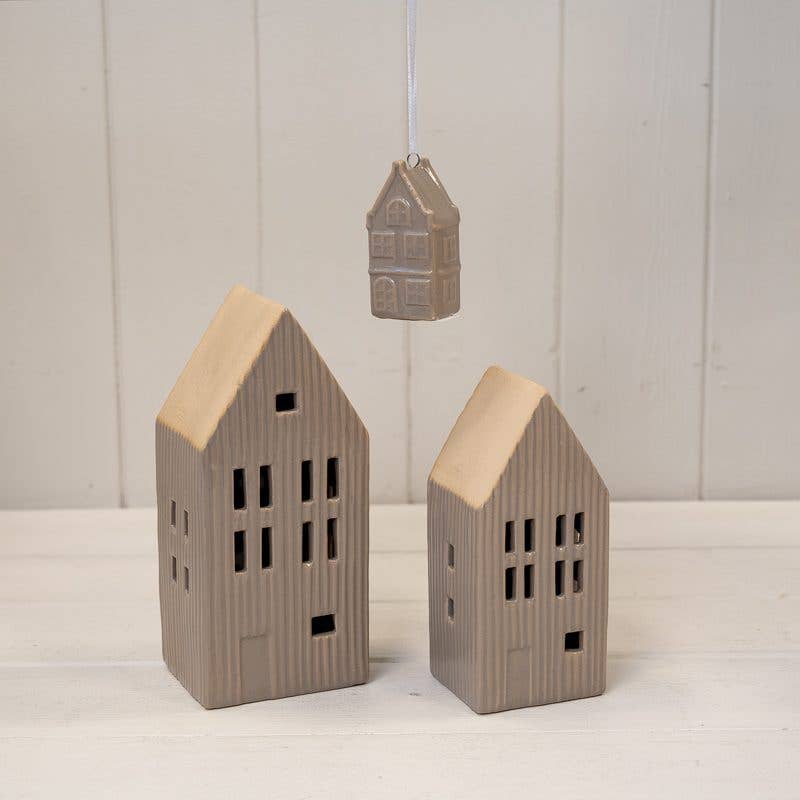 Three small house-shaped decorations on a white surface with a light gray background