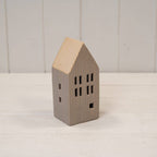 Small house-shaped ceramic ornament on a white surface with a light wooden roof.