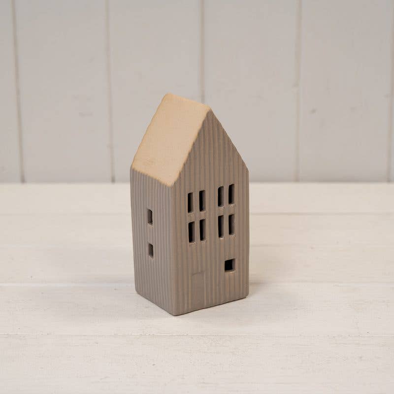 Small house-shaped ceramic ornament on a white surface with a light wooden roof.